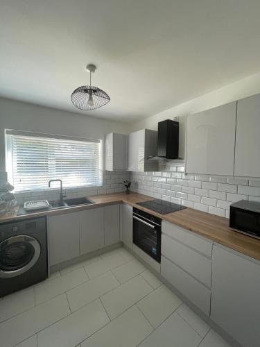 a kitchen with white cabinets and a sink and a dishwasher at Art's place in Royal Tunbridge Wells