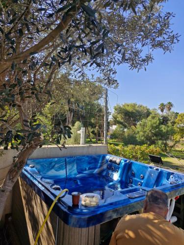 a man sitting in a blue tub under a tree at aqueduct villa cesarea jacuzzi in Caesarea