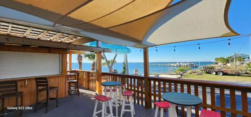 a patio with tables and stools on a deck with the ocean at Quality Inn & Suites Gulf Breeze Bayside near Pensacola Beach in Gulf Breeze