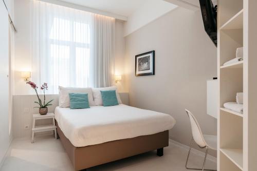 ein kleines Schlafzimmer mit einem Bett und einem Fenster in der Unterkunft Leopold Hotel Ostend in Ostende