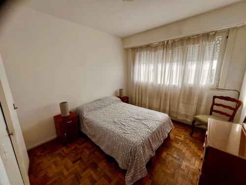 Un dormitorio con una cama y una silla y una ventana. en Departamento Zona Varese Piso 12, en Mar del Plata
