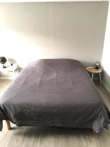 - un lit avec une couette noire dans une chambre dans l'établissement Fleur de lumiere, au Creusot