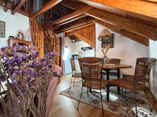 a dining room with a table and chairs and purple flowers at El rincón de Benás in Anciles