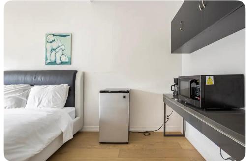 a white bedroom with a bed and a microwave at Charming one bed one bath privet studio in Tarzana