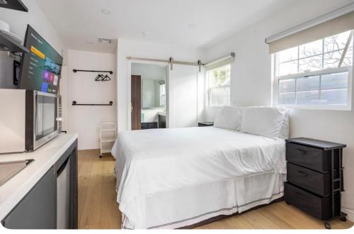 a bedroom with a white bed and a television at Charming one bed one bath privet studio in Tarzana