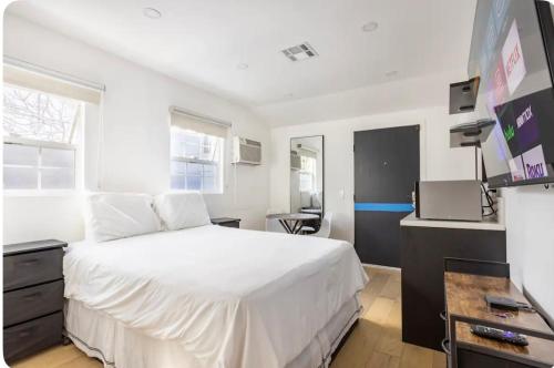 a bedroom with a large white bed and a desk at Charming one bed one bath privet studio in Tarzana