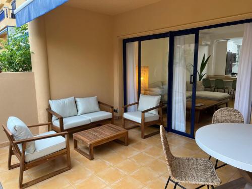 een woonkamer met een bank, stoelen en een tafel bij Meloneras Garden Bungalow in Meloneras