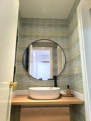 a bathroom with a round mirror and a sink at Meloneras Garden Bungalow in Meloneras