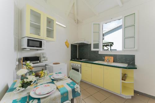 a kitchen with yellow cabinets and a table with plates on it at Studio Les Colibris in Sainte-Anne