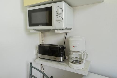 a microwave and a toaster oven on a shelf at Studio Les Colibris in Sainte-Anne
