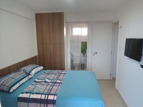 a bedroom with a bed and a television and a bathroom at Beach Village Residence in Fortaleza