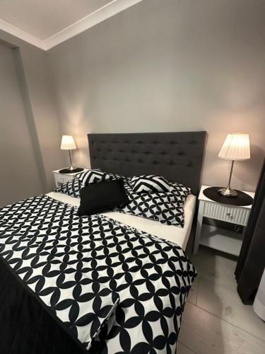a bedroom with a black and white bed and two lamps at Saviano Mare Villa in Międzyzdroje