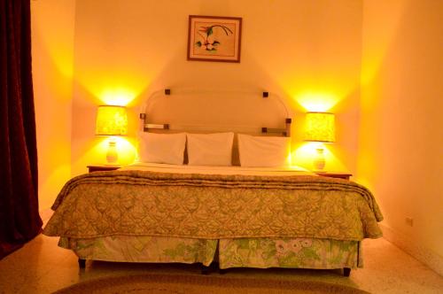a bedroom with a bed with two lamps on it at Sahara dela Mer Inn in Montego Bay
