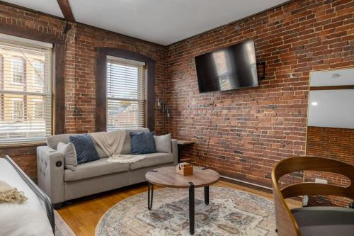 a living room with a couch and a brick wall at Newburyport Flat Downtown Living King Bed in Newburyport