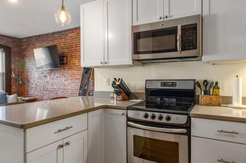 a kitchen with white cabinets and a stove top oven at Newburyport Flat Downtown Living King Bed in Newburyport