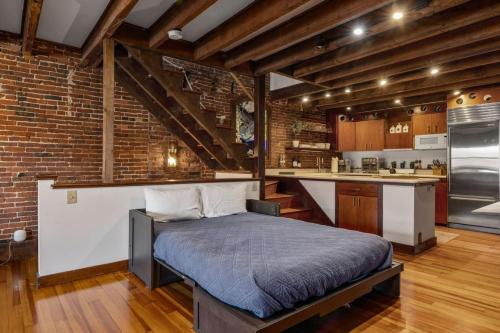 a bedroom with a bed and a brick wall at City Loft Group Getaway King Downtown Location in Newburyport