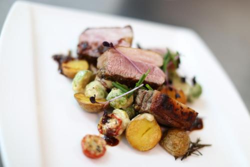 a white plate of food with meat and vegetables at Gastwirtschaft & Hotel Holzinger in Möllersdorf