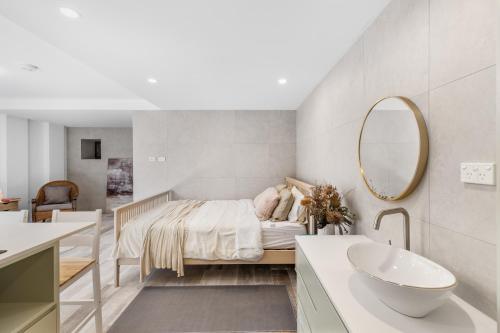 a bedroom with a bed and a sink and a mirror at Modern studio, Minutes to Ferry, City, CBD in Sydney