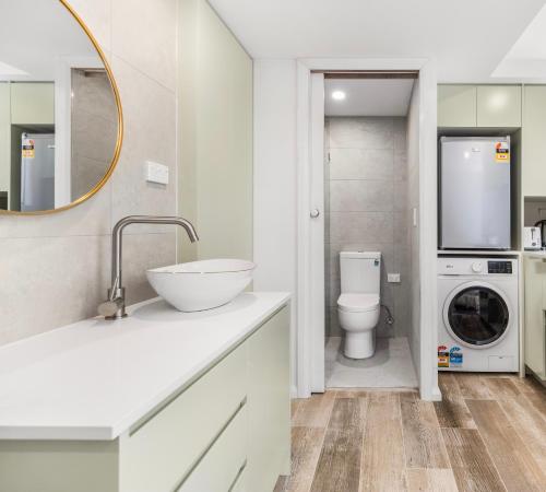 a bathroom with a sink and a washing machine at Modern studio, Minutes to Ferry, City, CBD in Sydney