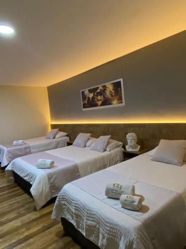 a hotel room with three beds with white sheets at Hotel Catedral Boutique Loft in Pasto