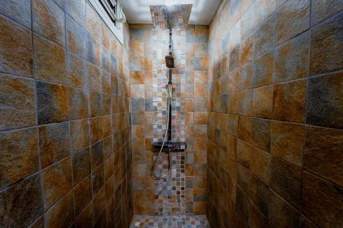 e bagno con doccia su una parete piastrellata. di Bas de villa le rêve éveillé a Le Robert