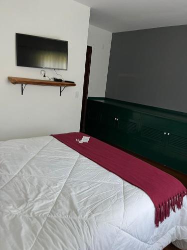 a bedroom with a bed with a red blanket on it at Recanto dos Vianas in Teresópolis