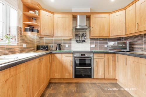 a kitchen with wooden cabinets and a stove top oven at Violetta Hemsby - Holiday home with Games Room in Hemsby
