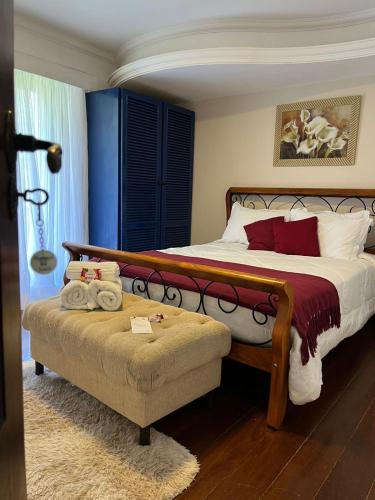 a bedroom with a large bed and a ottoman at Recanto dos Vianas in Teresópolis