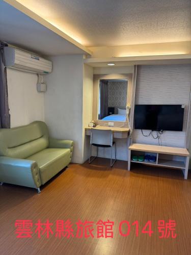 a living room with a green couch and a television at KD hotel in Douliu