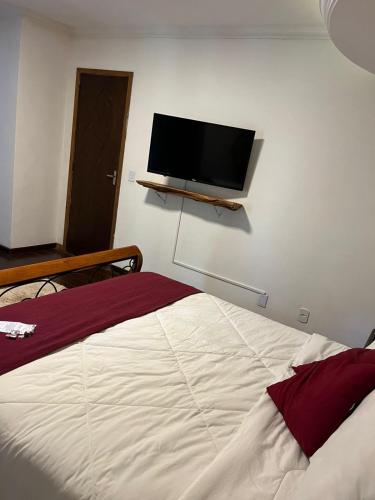 a bedroom with a bed and a flat screen tv on the wall at Recanto dos Vianas in Teresópolis