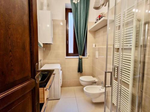 a bathroom with a toilet and a sink and a window at Anime Sante Apartment - Piazza Duomo in LʼAquila