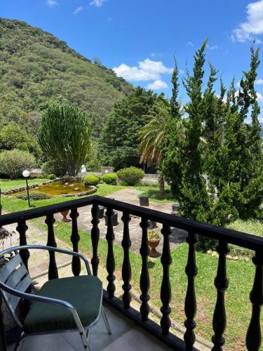 a chair on a balcony with a view of a garden at Recanto dos Vianas in Teresópolis