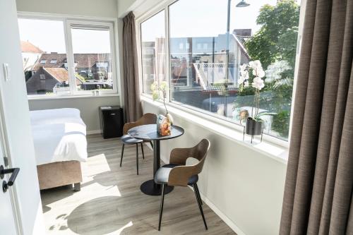 a room with a bed and a window with a table and chairs at Modern Suite with AC near Breda & Efteling in Raamsdonksveer