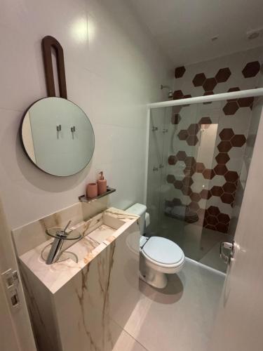 un bagno con un water, un lavandino e uno specchio di Cobertura magnífica frente mar a Florianópolis