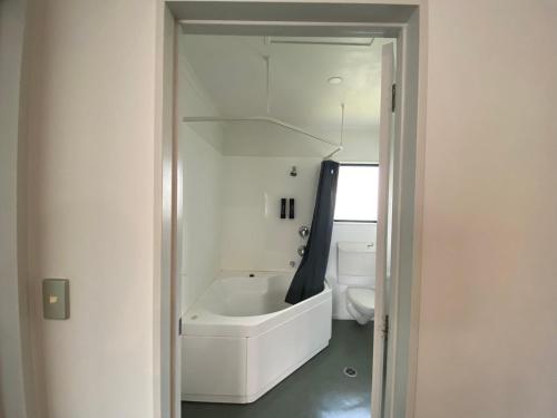 a white bathroom with a tub and a toilet at Camelot Motor Lodge and Conference Centre in Palmerston North