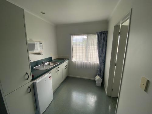 a small kitchen with a sink and a window at Camelot Motor Lodge and Conference Centre in Palmerston North