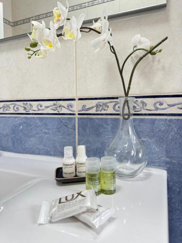 a vase with white flowers on a bathroom sink at Villa Bonita Guesthouse Albufeira Old Town in Albufeira
