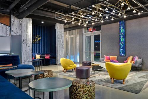 a lobby with yellow chairs and tables at Aloft Secaucus Meadowlands in Secaucus