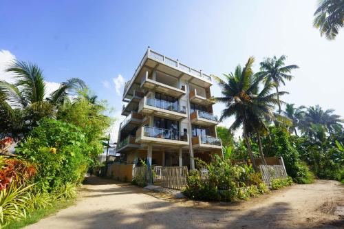 a tall building with palm trees in front of it at La Dolce Vita Weligama in Weligama
