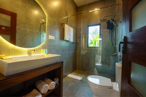 a bathroom with a sink and a toilet and a mirror at La Dolce Vita Weligama in Weligama