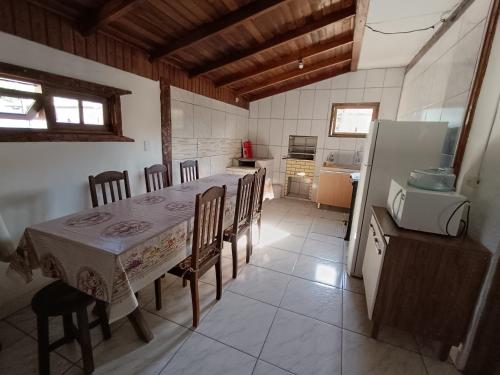 a kitchen with a table and chairs and a refrigerator at Casa de descanso a 4km - 5 min da Guarda do Embaú in Palhoça