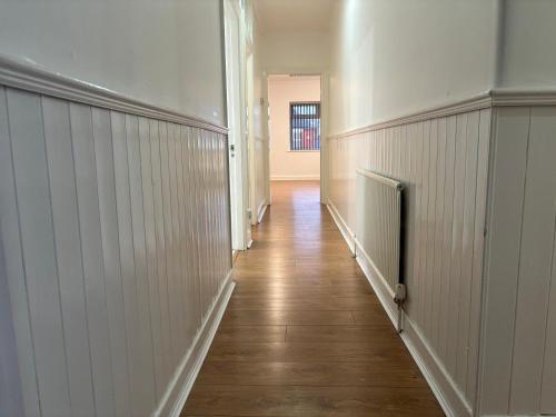 a hallway with white walls and a wooden floor at Del Apartments in Warrington