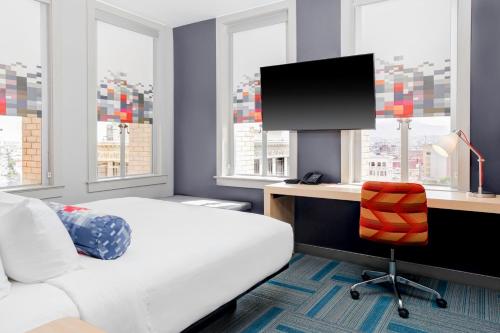 a bedroom with a bed and a desk with a television at Aloft El Paso Downtown in El Paso