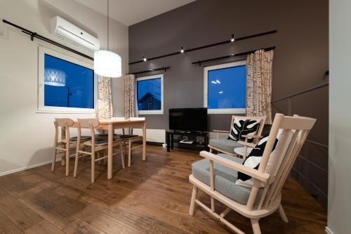 a living room with chairs and a table and a television at Niseko Highland Cottages in Niseko