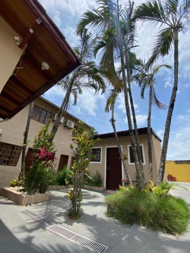 a house with palm trees in front of it at Pousada Kembali Maresias in Maresias