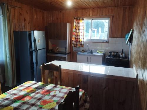 a kitchen with a refrigerator and a table in it at Cabañas encanto de Chovellen in Pelluhue