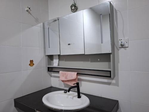 a white bathroom with a sink and a mirror at Comfort homestay68 in Sitiawan