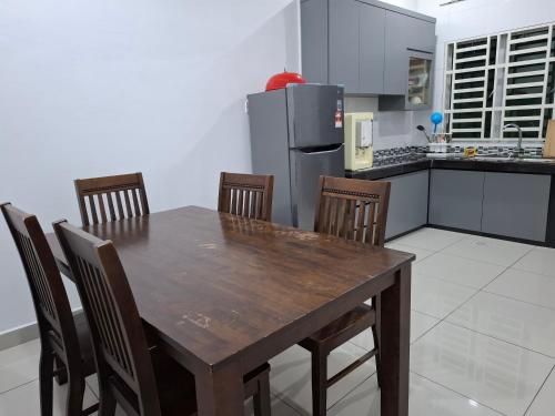 a kitchen with a wooden table with chairs and a refrigerator at Comfort homestay68 in Sitiawan