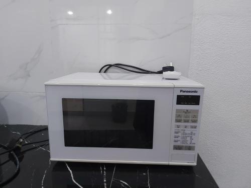 a white microwave sitting on top of a counter at Comfort homestay68 in Sitiawan