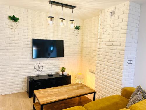 un salon avec une télévision sur un mur de briques blanches dans l'établissement La Vallée des Lumières - 5 minutes de Disneyland, à Magny-le-Hongre
